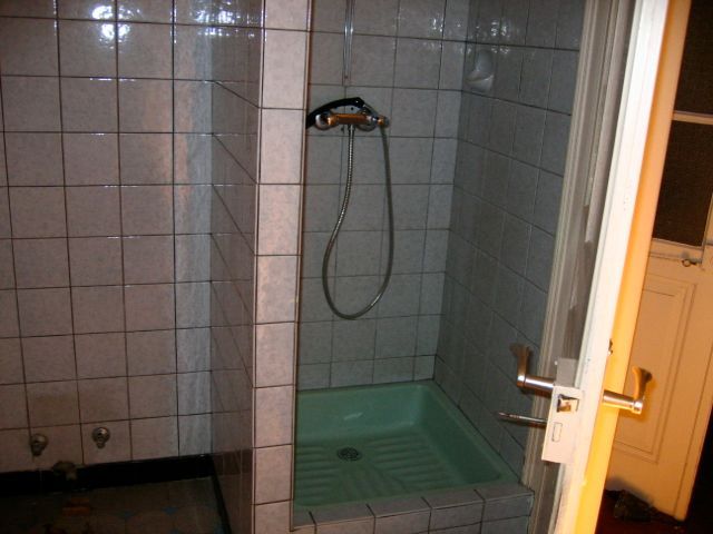 Une salle de bain avec du carrelage blanc et une cabine de douche verte