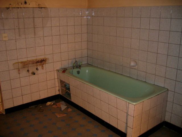 Une salle de bain avec du carrelage blanc et une baignoire verte
