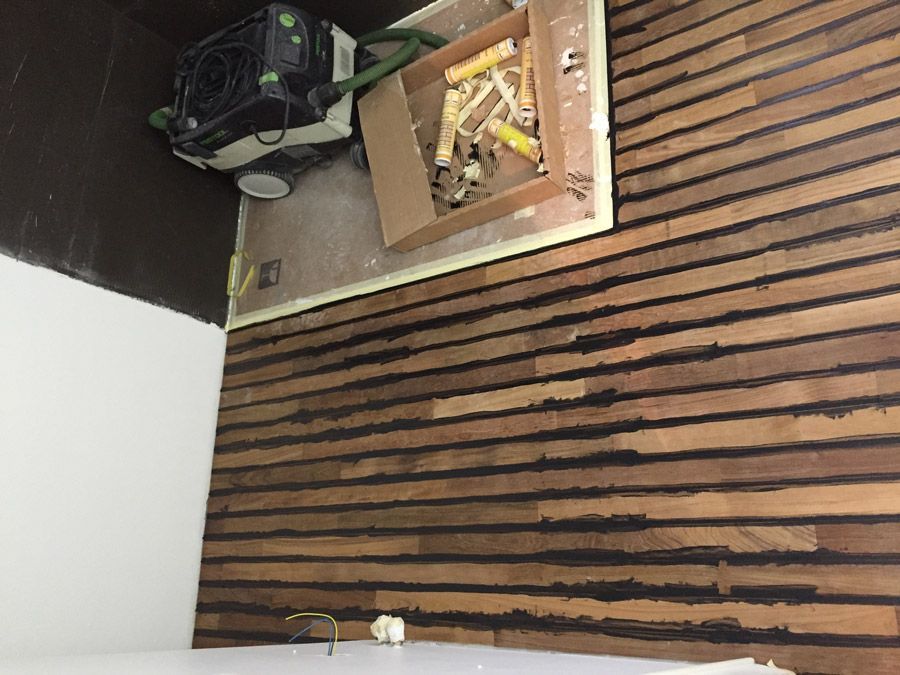 Un aspirateur est posé sur un plancher en bois à côté d'une boîte à outils.