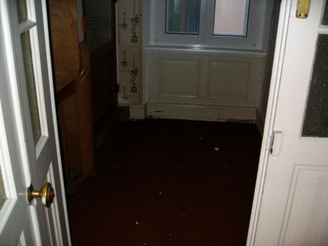 Un couloir avec une porte blanche et une fenêtre