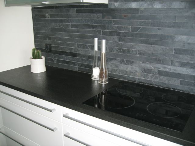 Une cuisine avec un comptoir noir et une cuisinière noire