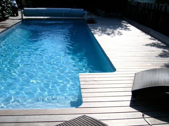 Une grande piscine est entourée d'une terrasse en bois