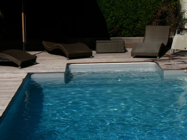 Une piscine avec des chaises et des parasols autour