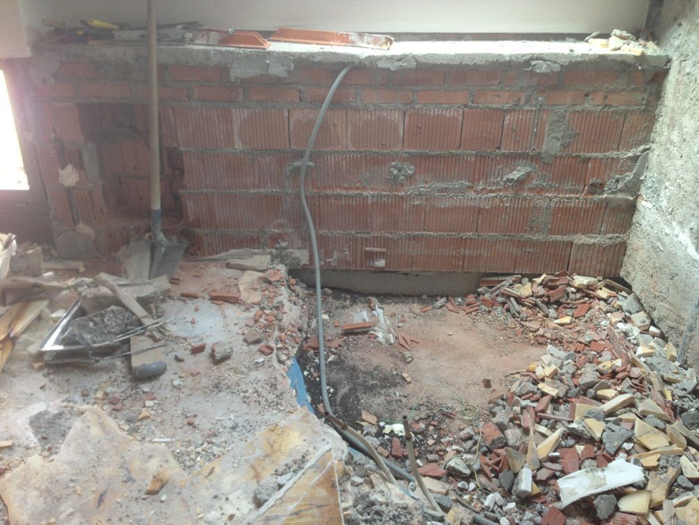 Une pièce avec un mur de briques et beaucoup de gravats sur le sol