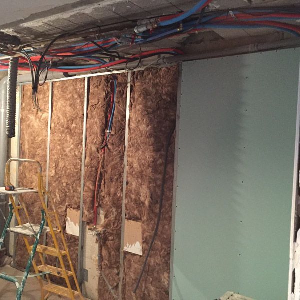 Une pièce avec une échelle et beaucoup de fils suspendus au plafond.