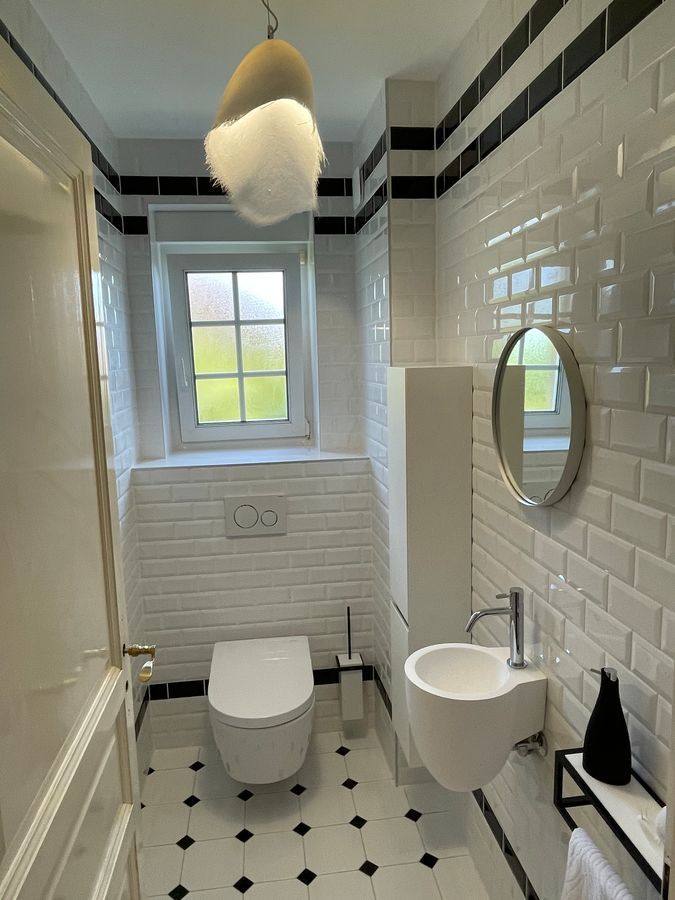 Une salle de bain avec WC, lavabo, miroir et fenêtre.