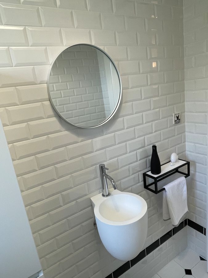 Une salle de bain avec un lavabo et un miroir au mur.