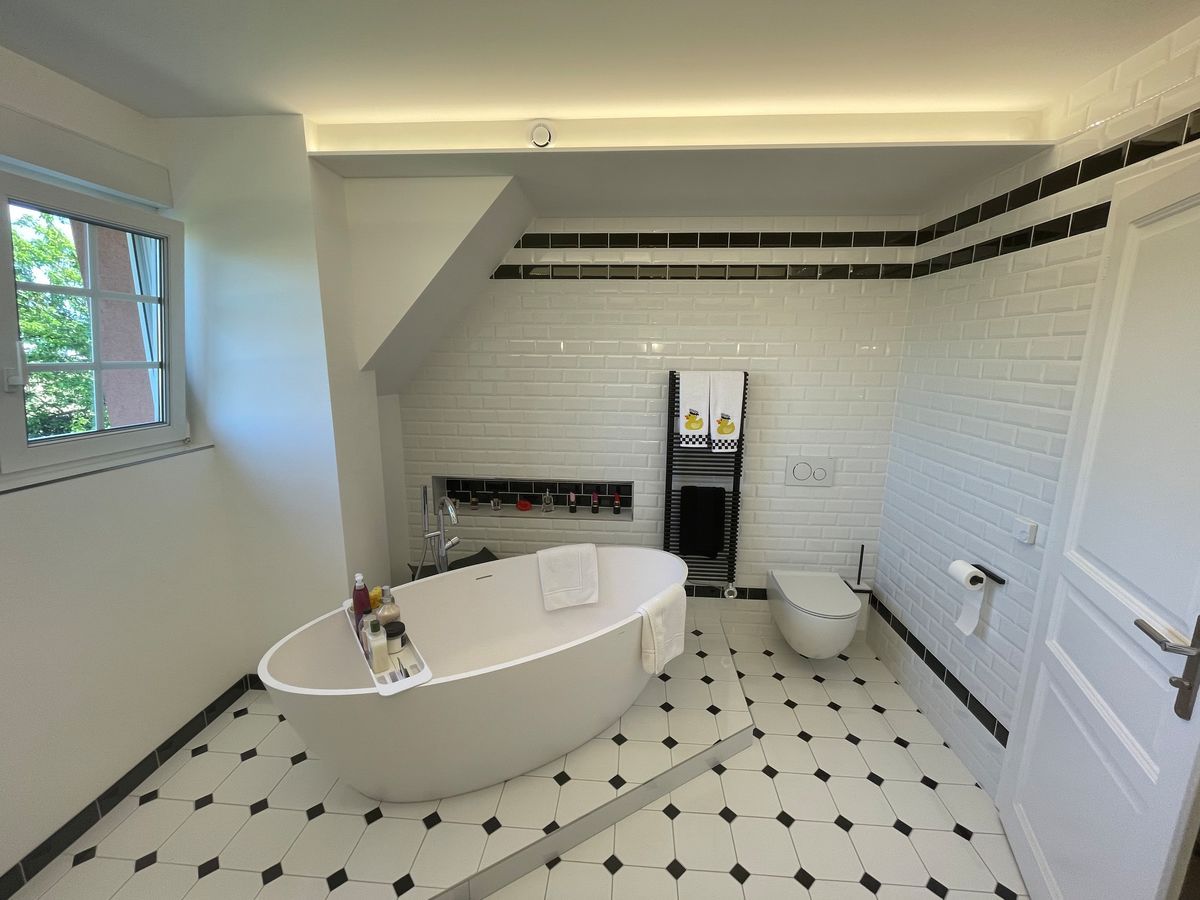 Une salle de bain avec baignoire, toilettes et fenêtre.