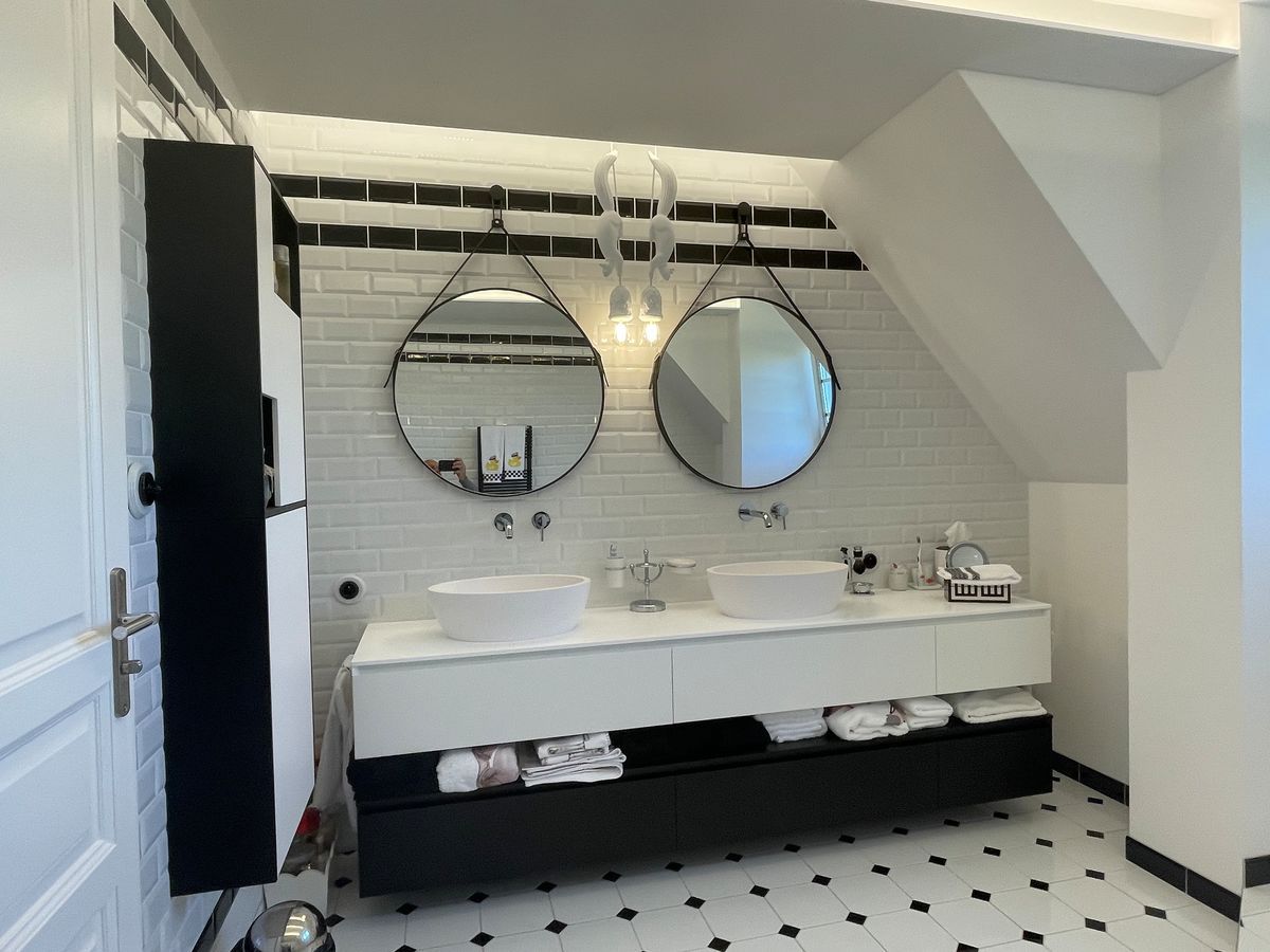 Une salle de bain avec deux lavabos et deux miroirs.