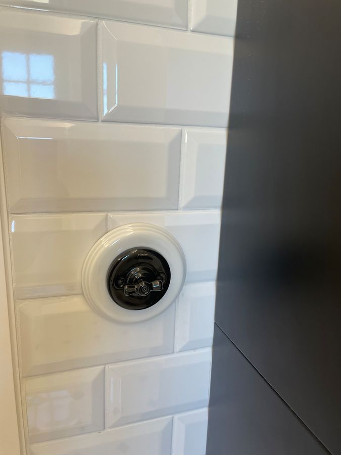 Un gros plan d'un interrupteur sur un mur carrelé blanc.