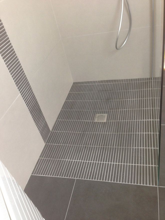 Une salle de bain avec une douche à l'italienne et un drain.