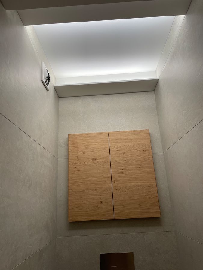 Une salle de bain avec un mur en bois et un plafond blanc