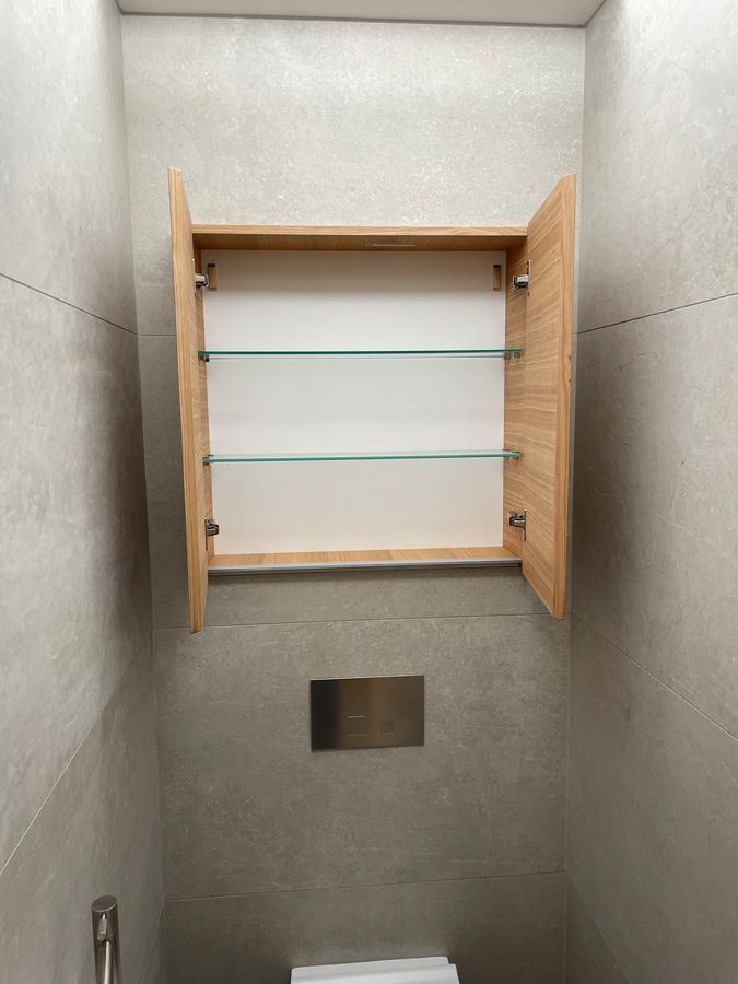 Une salle de bain avec une armoire à pharmacie au dessus des toilettes.