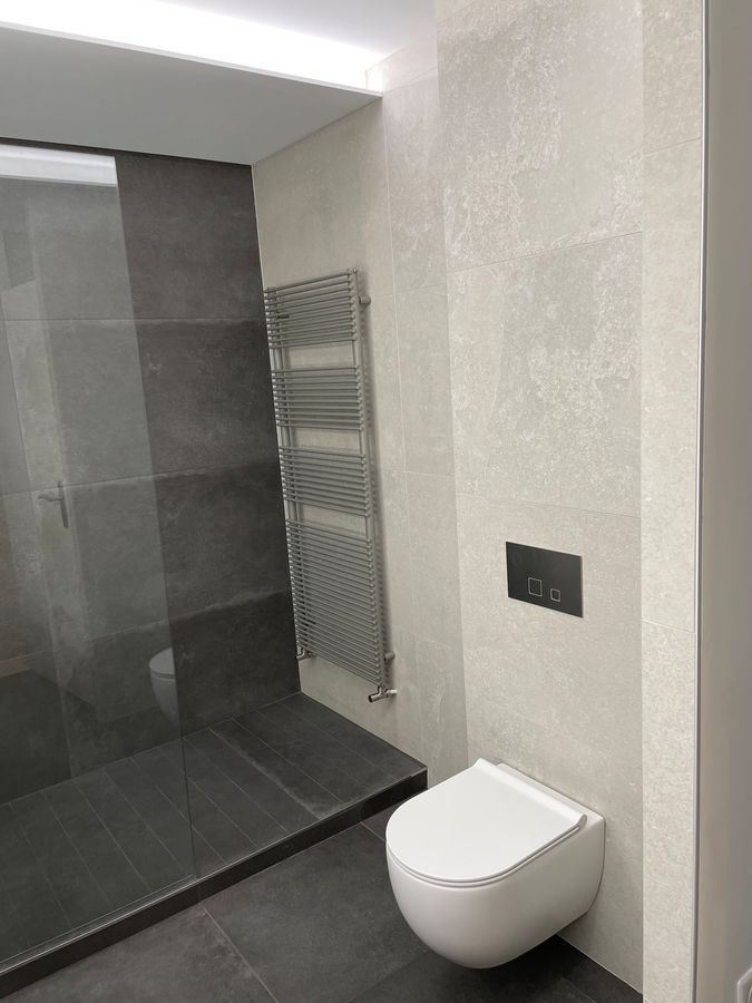 Une salle de bain avec WC, douche et sèche-serviettes.