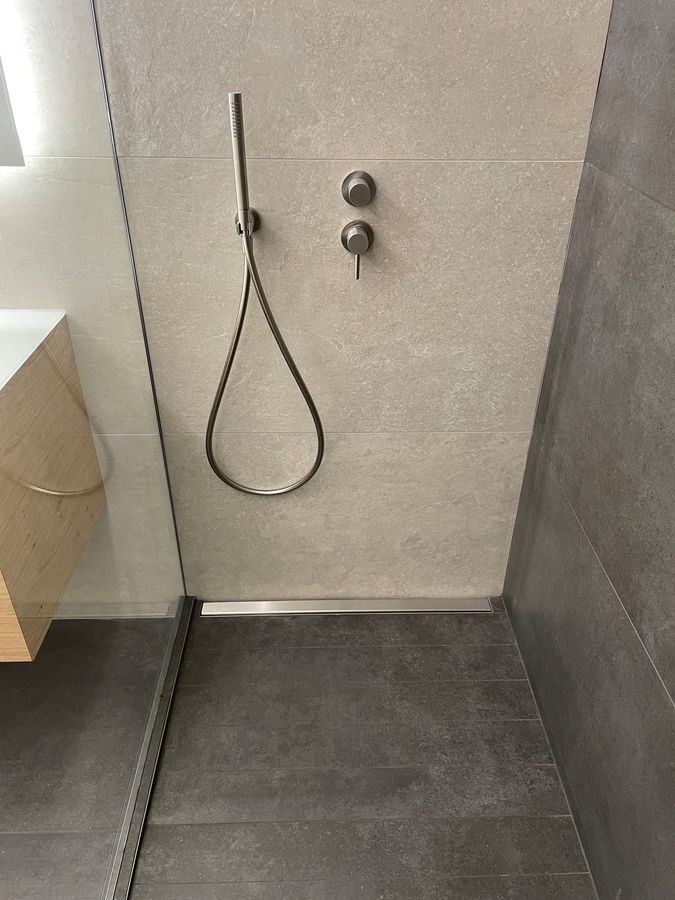 Une salle de bain avec une douche à l'italienne et un lavabo.