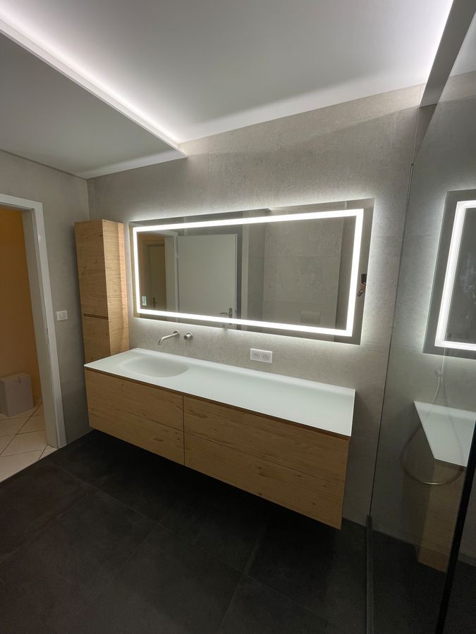 Une salle de bain avec un grand miroir et un lavabo.
