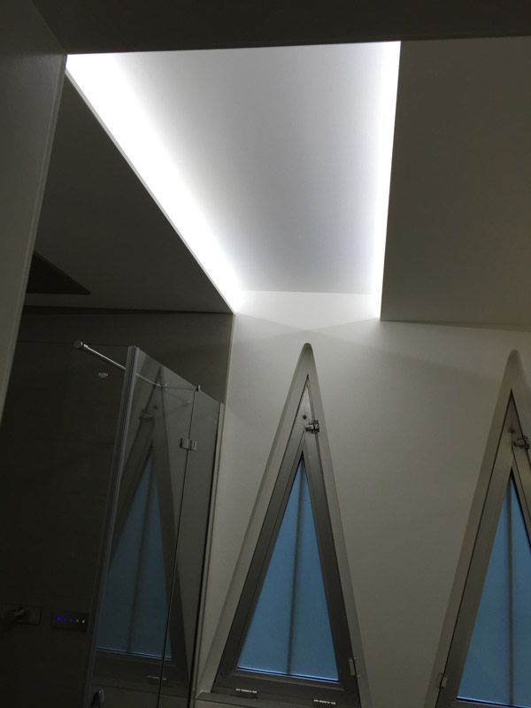 Une pièce avec une fenêtre en forme de triangle et une lumière au plafond.