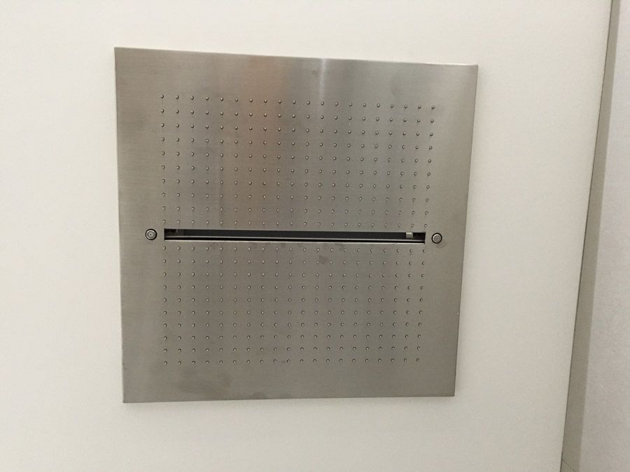 Une pomme de douche en acier inoxydable est accrochée à un mur blanc