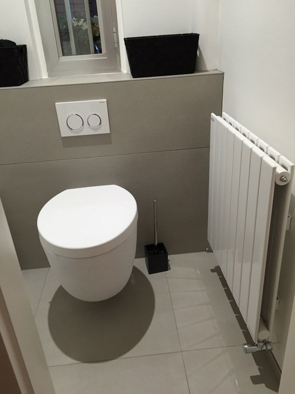 Une salle de bain avec WC, radiateur et miroir.