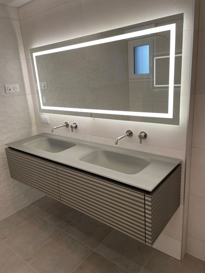 Une salle de bain avec deux lavabos et un grand miroir.