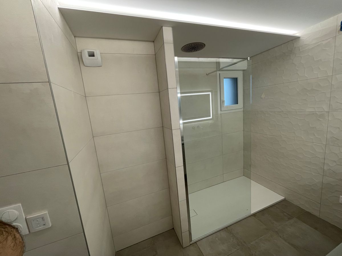 Une salle de bain avec douche à l'italienne et fenêtre.