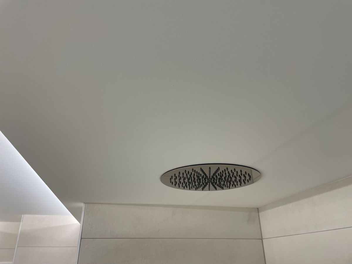 Une pomme de douche est suspendue au plafond d'une salle de bain.