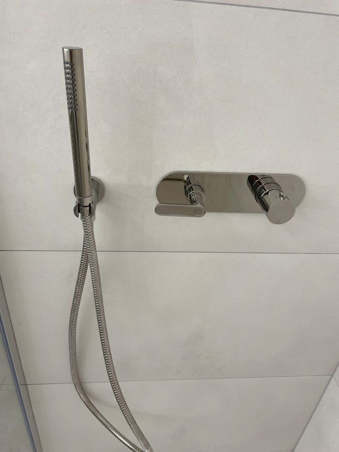 Une pomme de douche avec un tuyau attaché est accrochée à un mur.
