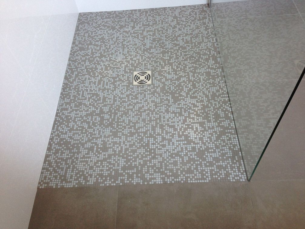 Une douche à l'italienne avec un sol carrelé et un drain