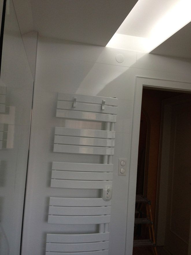 Un porte-serviettes blanc est accroché sur un mur blanc dans une salle de bain.