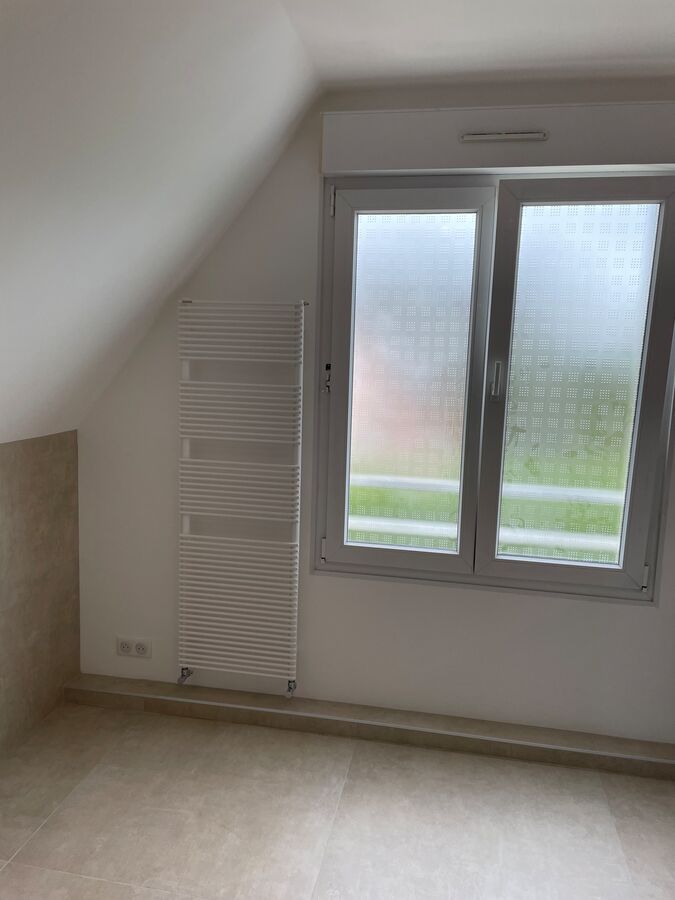 Une pièce vide avec deux fenêtres et un radiateur.