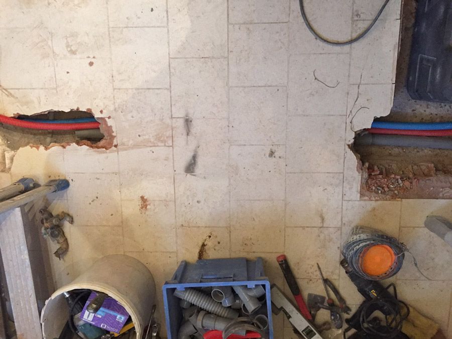 Un seau rempli de tuyaux et d'outils repose sur un sol carrelé