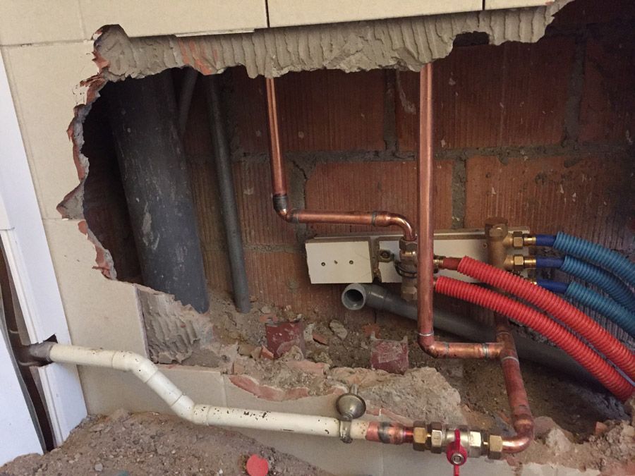 Un mur de briques avec un trou dedans et des tuyaux en cuivre qui en sortent.