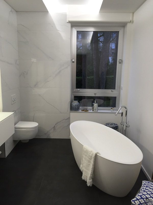 Une salle de bain avec baignoire, WC, lavabo et fenêtre.