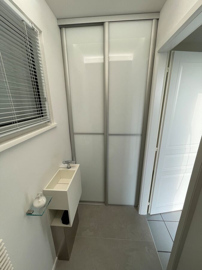 Une salle de bain avec un lavabo et des portes coulissantes en verre.