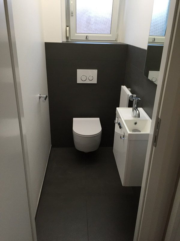 Une salle de bain avec WC, lavabo et miroir.