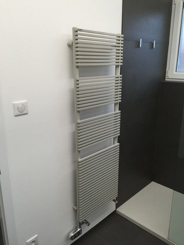 Un porte-serviettes blanc est accroché sur un mur blanc dans une salle de bain.