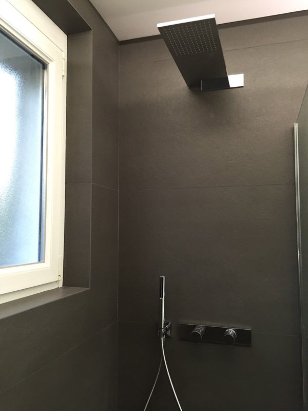 Une pomme de douche est suspendue au plafond dans une salle de bain à côté d'une fenêtre.