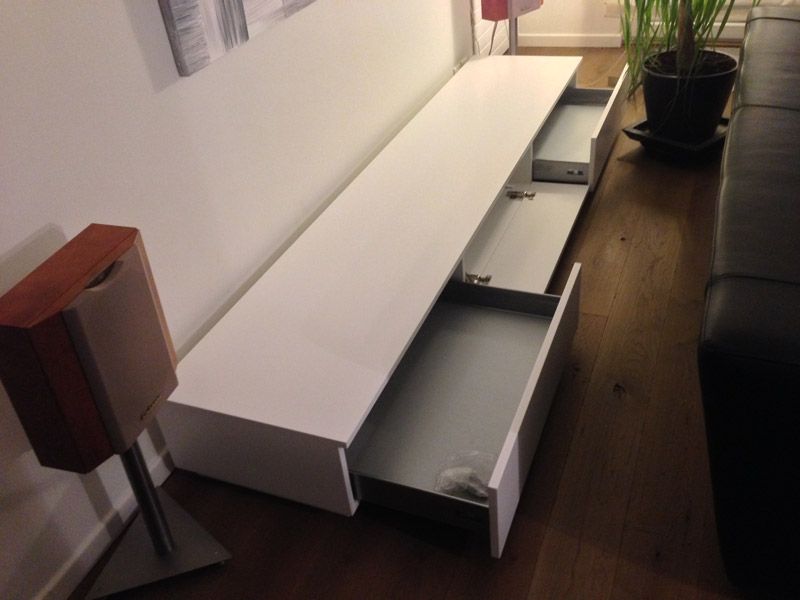 Un centre de divertissement blanc avec des tiroirs ouverts dans un salon