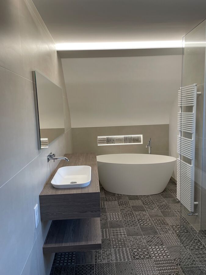 Une salle de bain avec baignoire, lavabo, miroir et porte-serviettes.