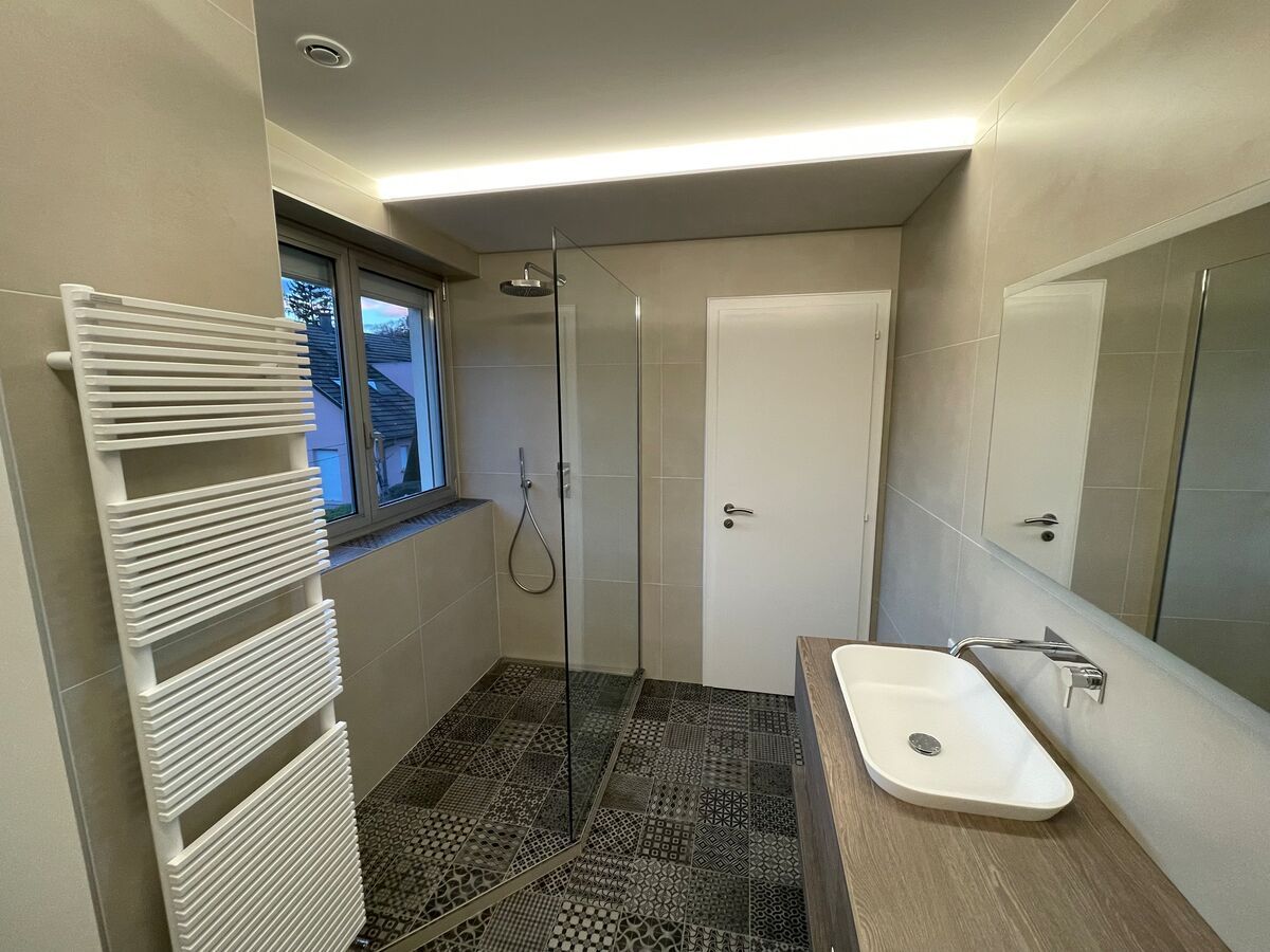 Une salle de bain avec lavabo, miroir et porte-serviettes.