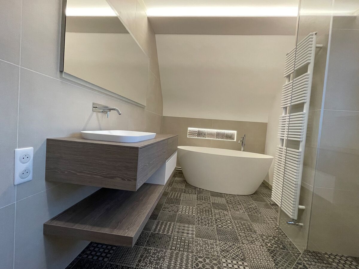 Une salle de bain avec lavabo, baignoire, miroir et porte-serviettes.