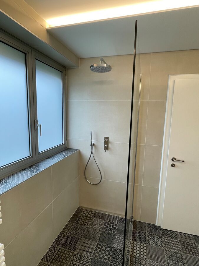 Une salle de bain avec douche à l'italienne et fenêtre.