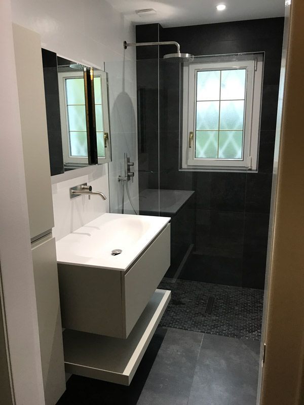 Une salle de bain avec lavabo, miroir et douche.