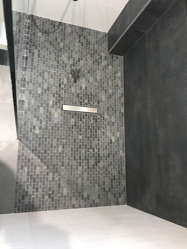 Une salle de bain avec douche à l'italienne et mur carrelé.