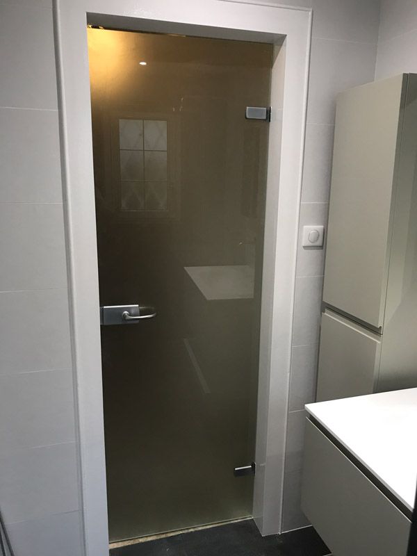 Une salle de bain avec une porte vitrée et un lavabo.
