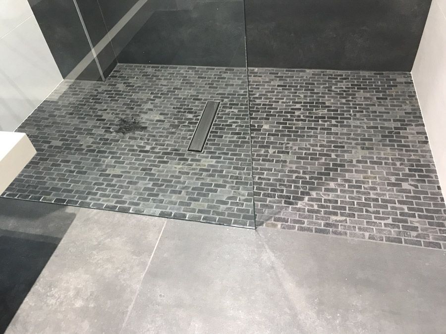 Une douche à l'italienne avec un sol carrelé et une porte vitrée.