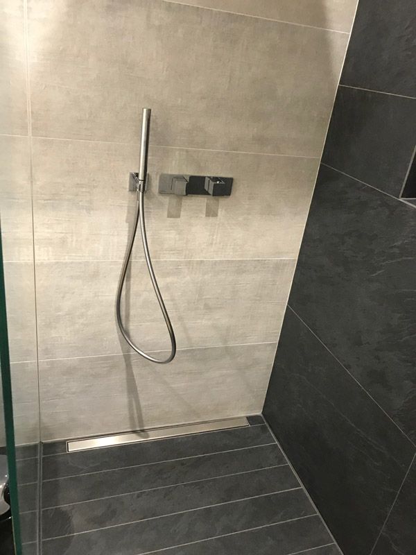 Une douche à l'italienne avec une porte vitrée et une pomme de douche.