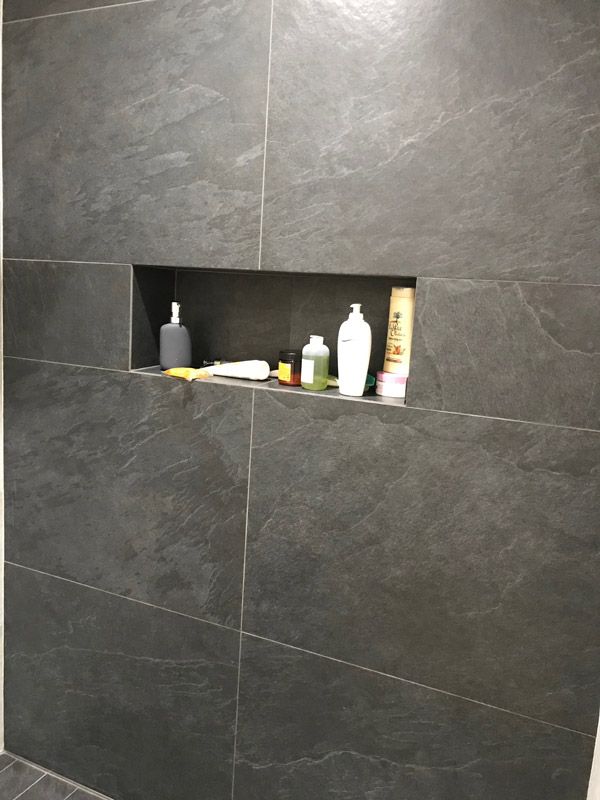 Une étagère dans une salle de bain avec des bouteilles dessus