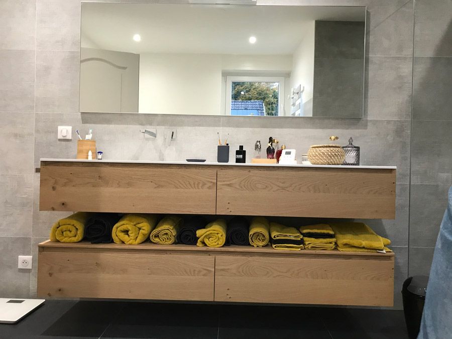 Une salle de bain avec un lavabo, un miroir et des armoires en bois.