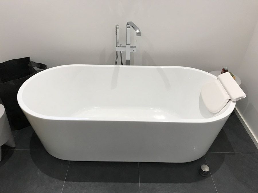 Une baignoire blanche est posée sur un sol carrelé dans une salle de bain.